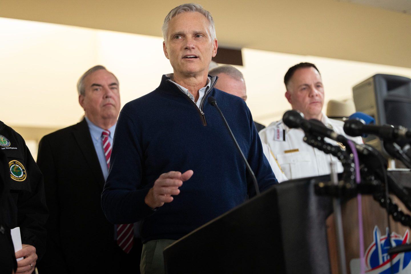 Robert Isom speaks at a podium while a group of people stand behind him.