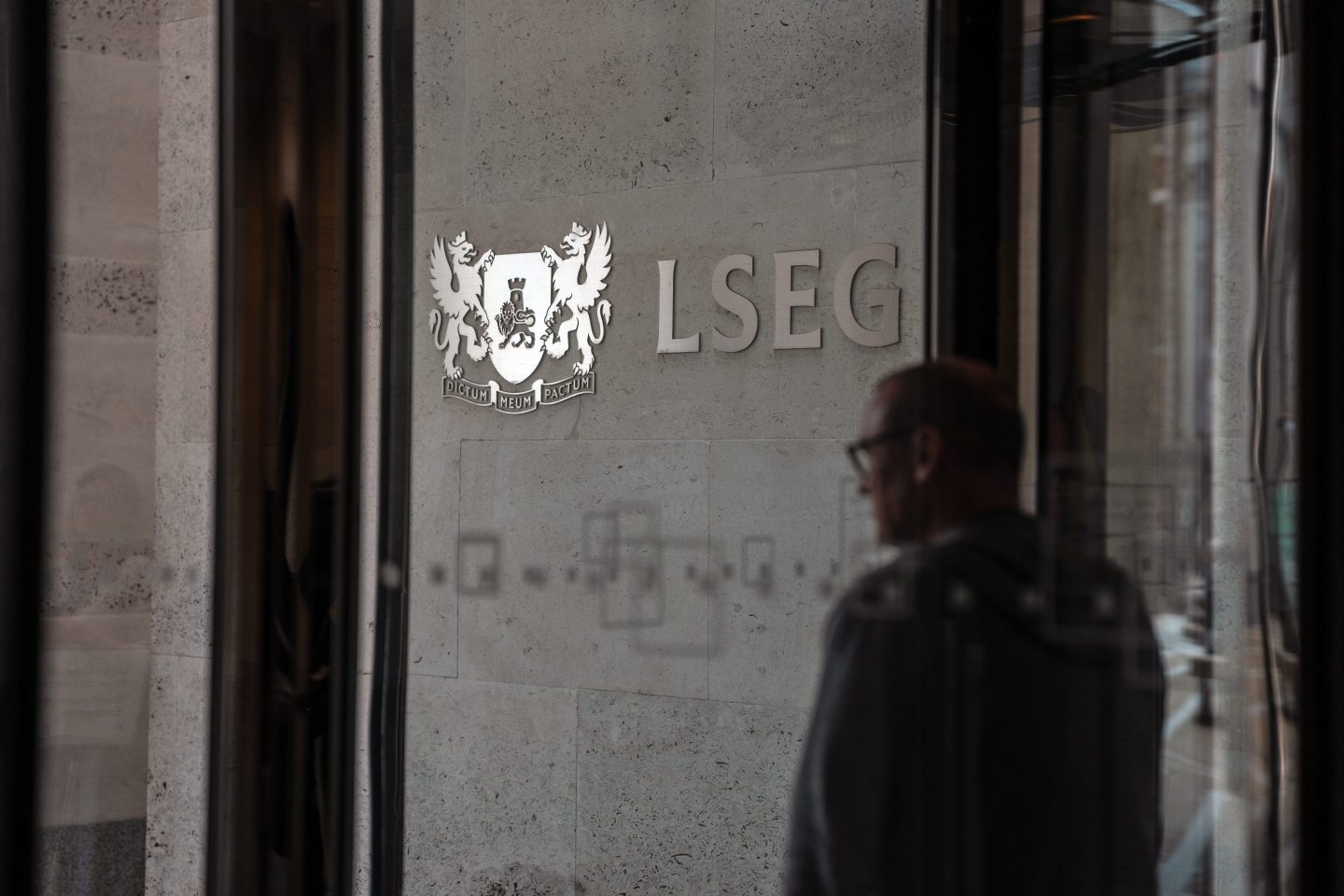 person passes a London Stock exchange Group logo at the London Stock Exchange