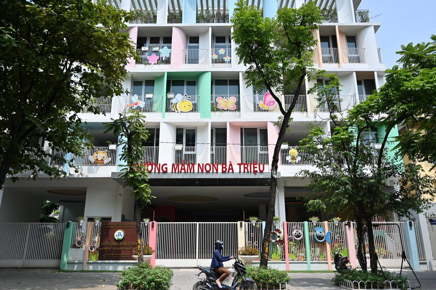 A girl rides a motorbike past the Ba Trieu kindergarten in Hanoi on June 4, 2025.