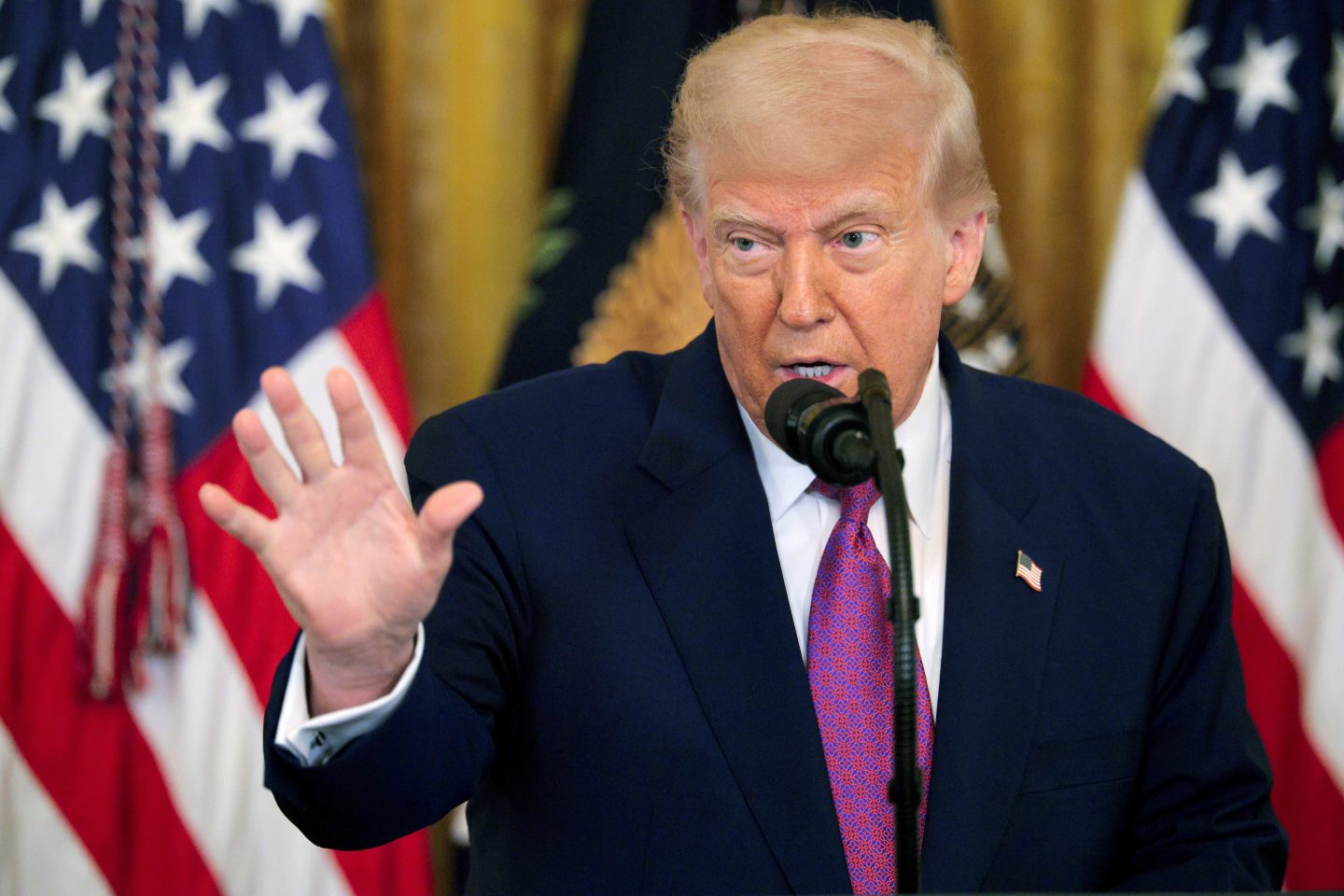 President Donald Trump holds up his hand during a press conference in June.