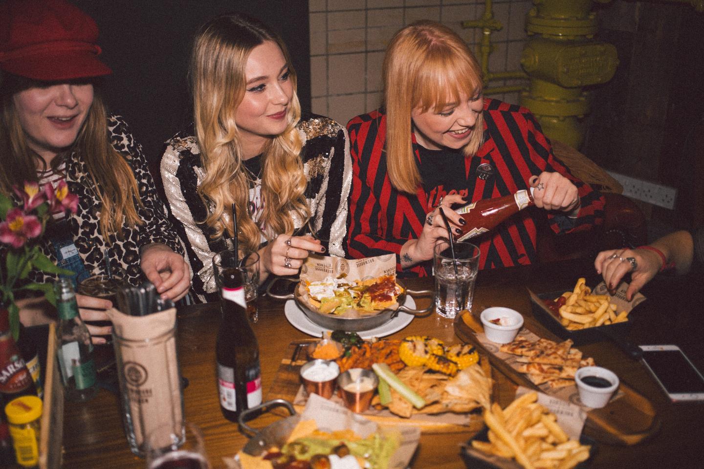 A group of young women sit around a table at a restaurant.