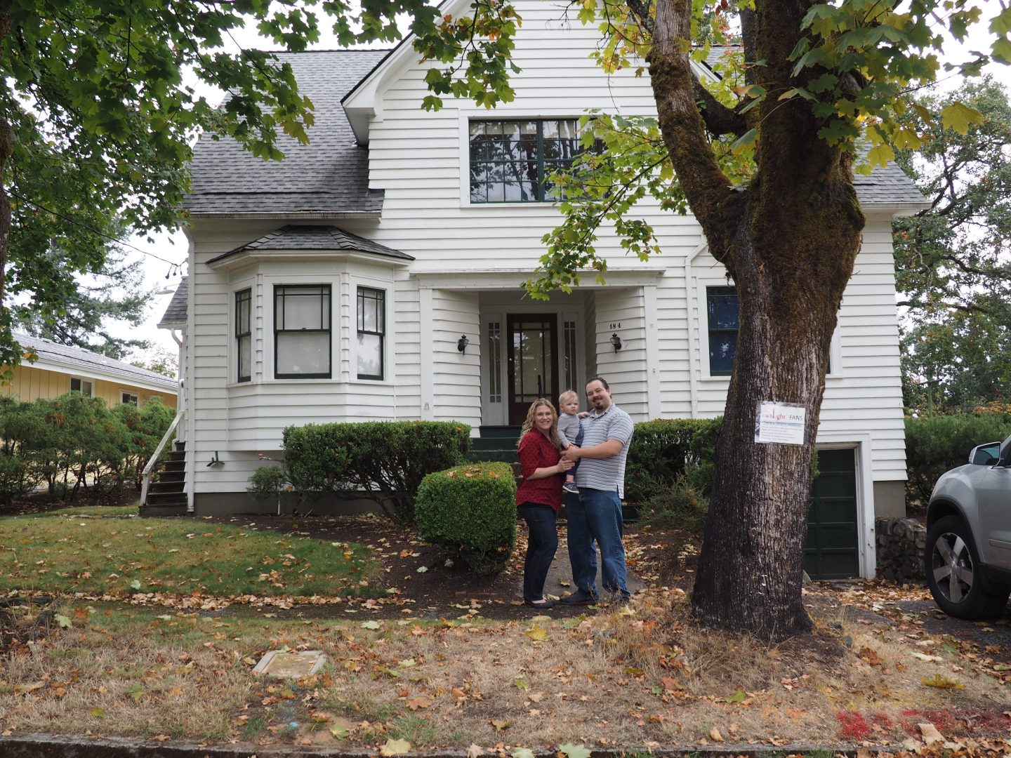 Amber and Dean Neufeld with their child in front of the Swan house.