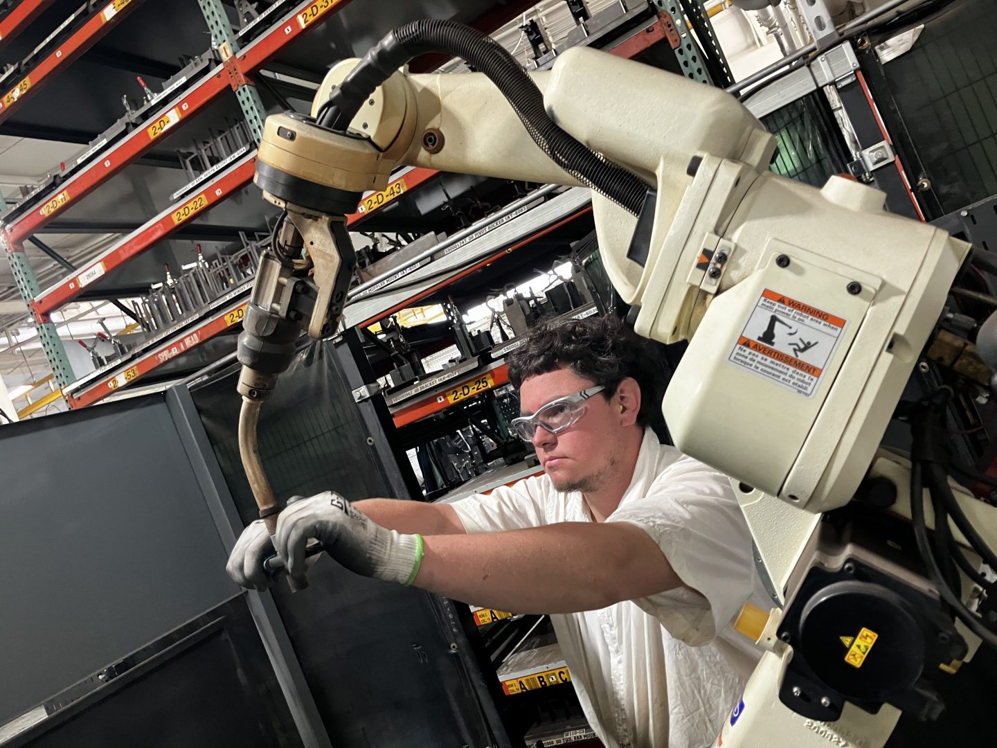Matthew Miller, 27, adjusts the contact tip on a robotic welding arm in the Flextur factory.