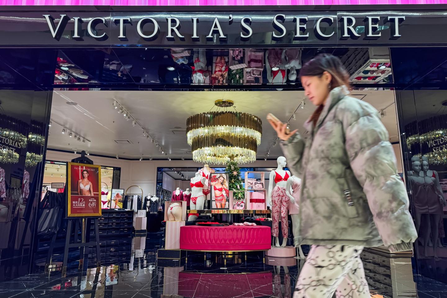 A shopper scrolls past a Victoria's Secret store