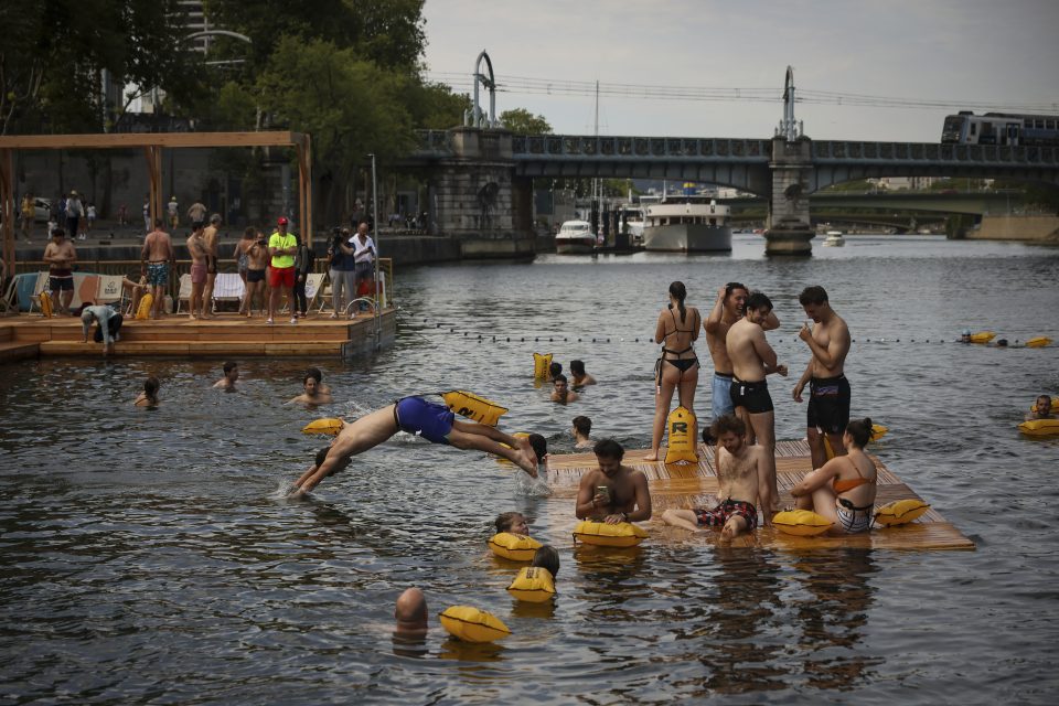 A man dives in the water as people swim at the Grenelle safe bathing site.