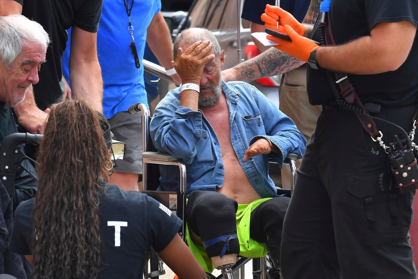 Michael Pimentel, center, a resident at the Gabriel House assisted living facility, in Fall River, Mass., receives assistance from an emergency medical worker, right, outside a temporary shelter, on July 14, 2025, in Fall River, following a fire that started late Sunday.