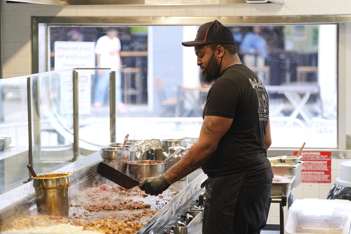Malik Everett fries beef for a cheesesteak at Jim's South St. in Philadelphia, on July 23, 2025.