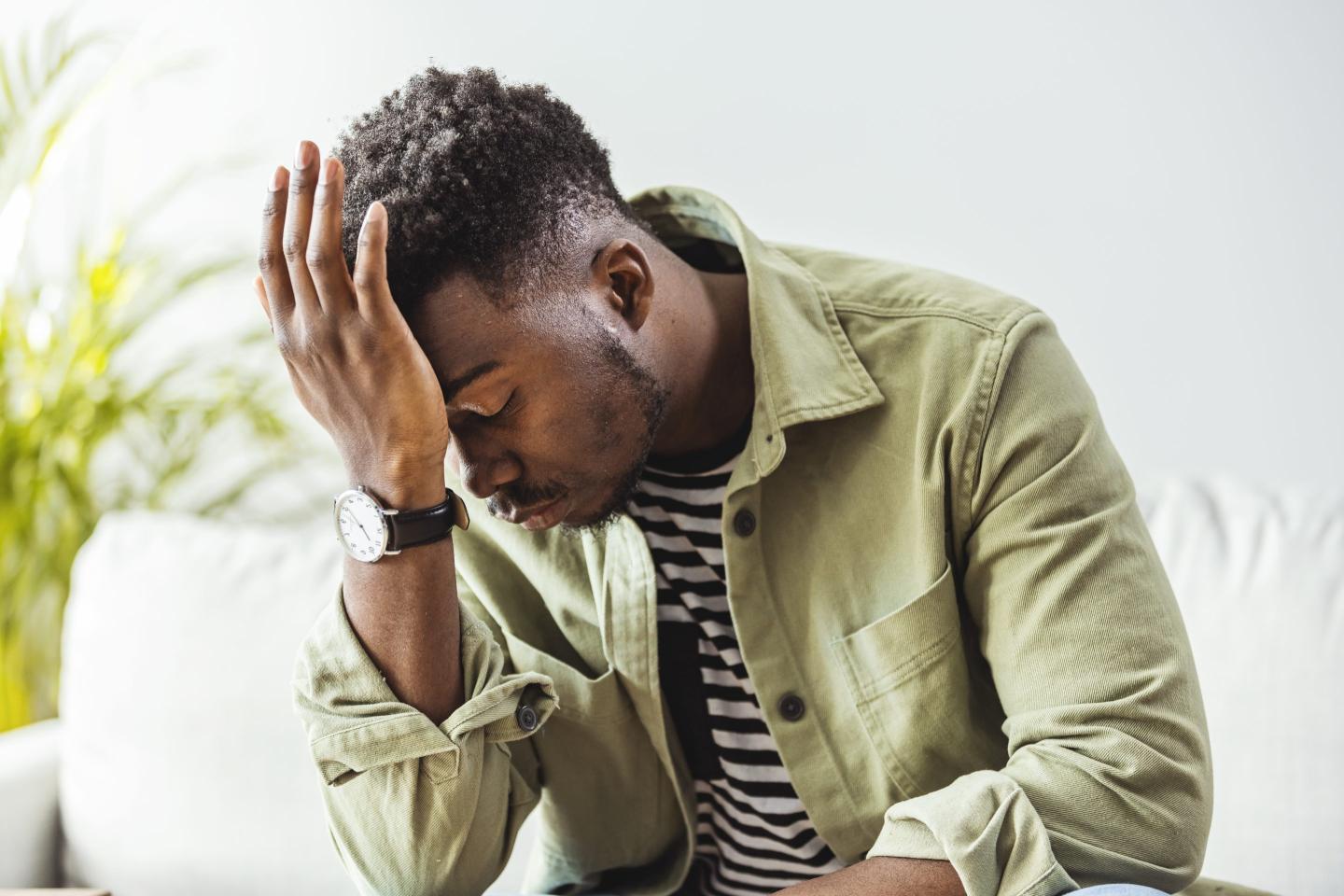 Distressed young man, with his palm to his head