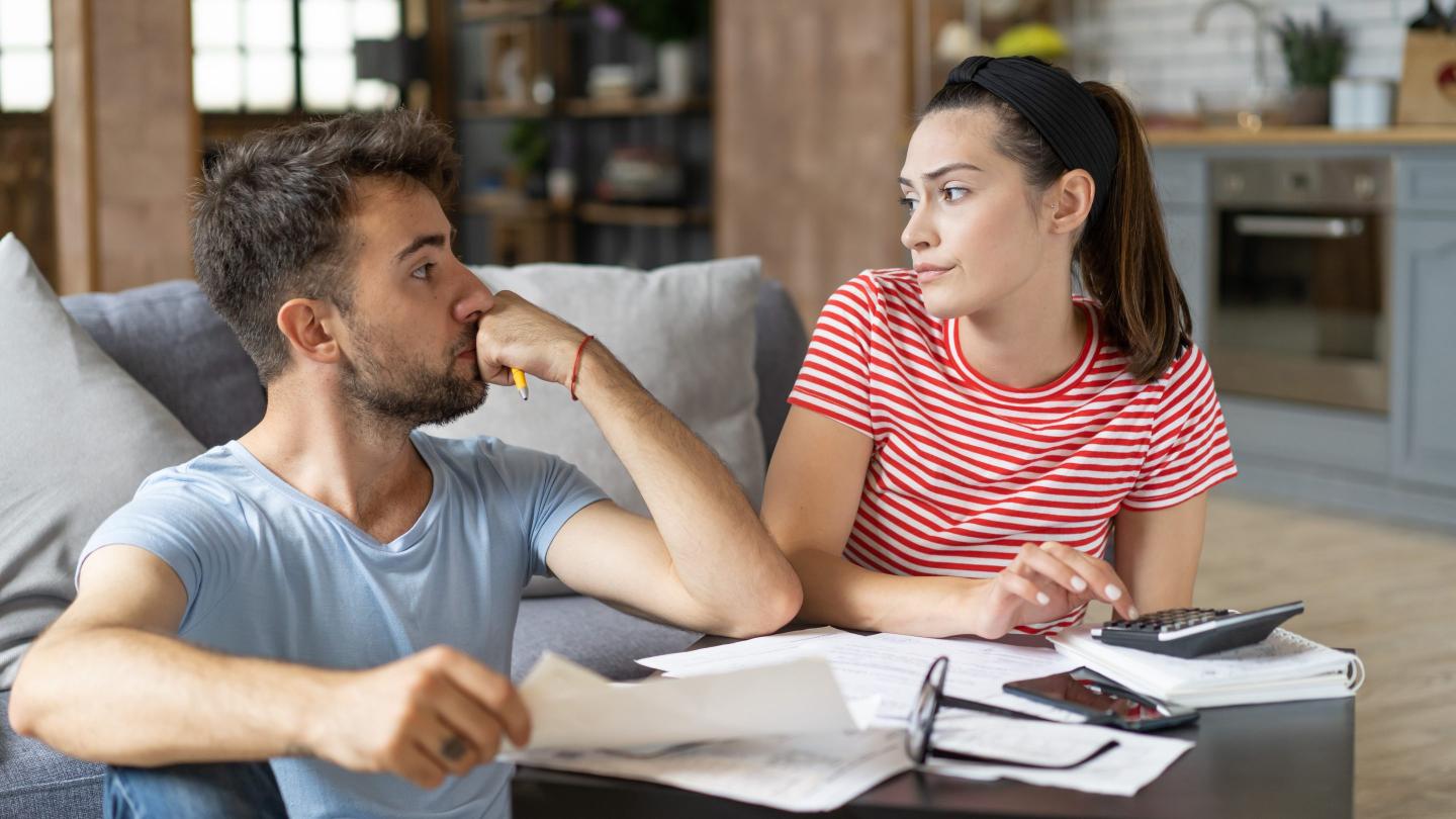 Frustrated concerned young couple calculating overspend budget