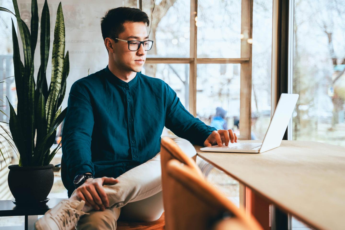 A progressive Asian businessman in modern casual clothing working in smart glasses
