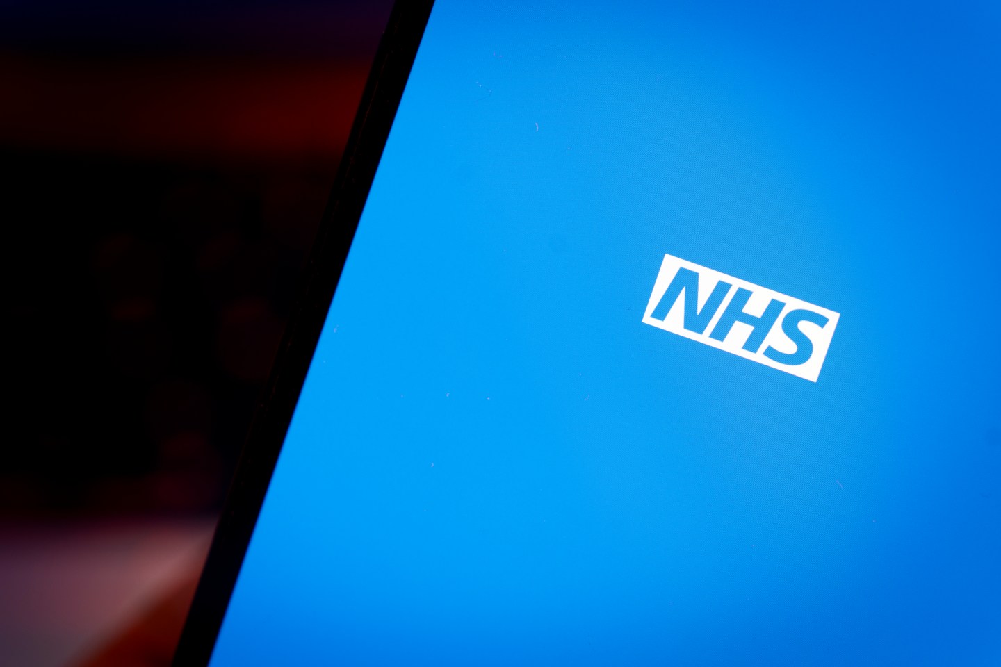 NHS logo on a phone screen.