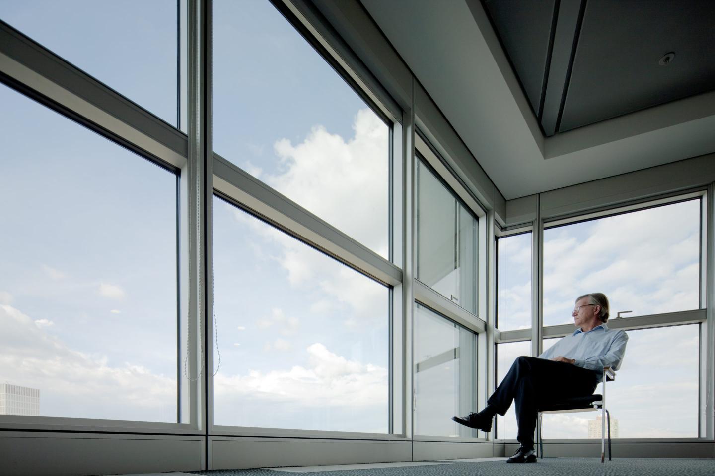 A man sits in an empty corner office