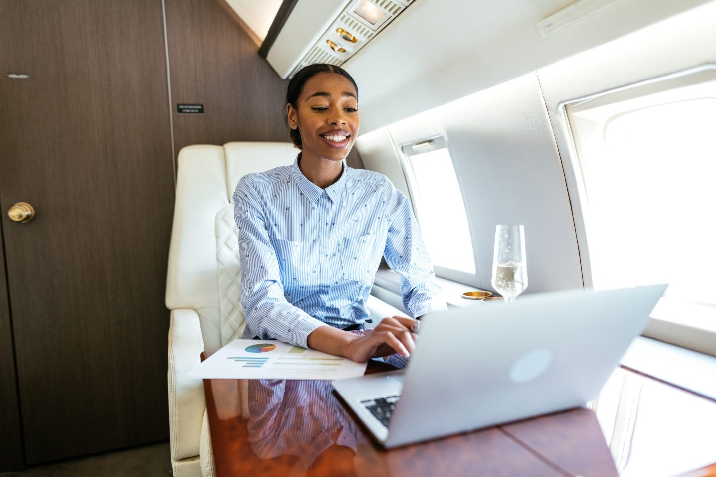 Business woman doing work on a laptop in a private jet.