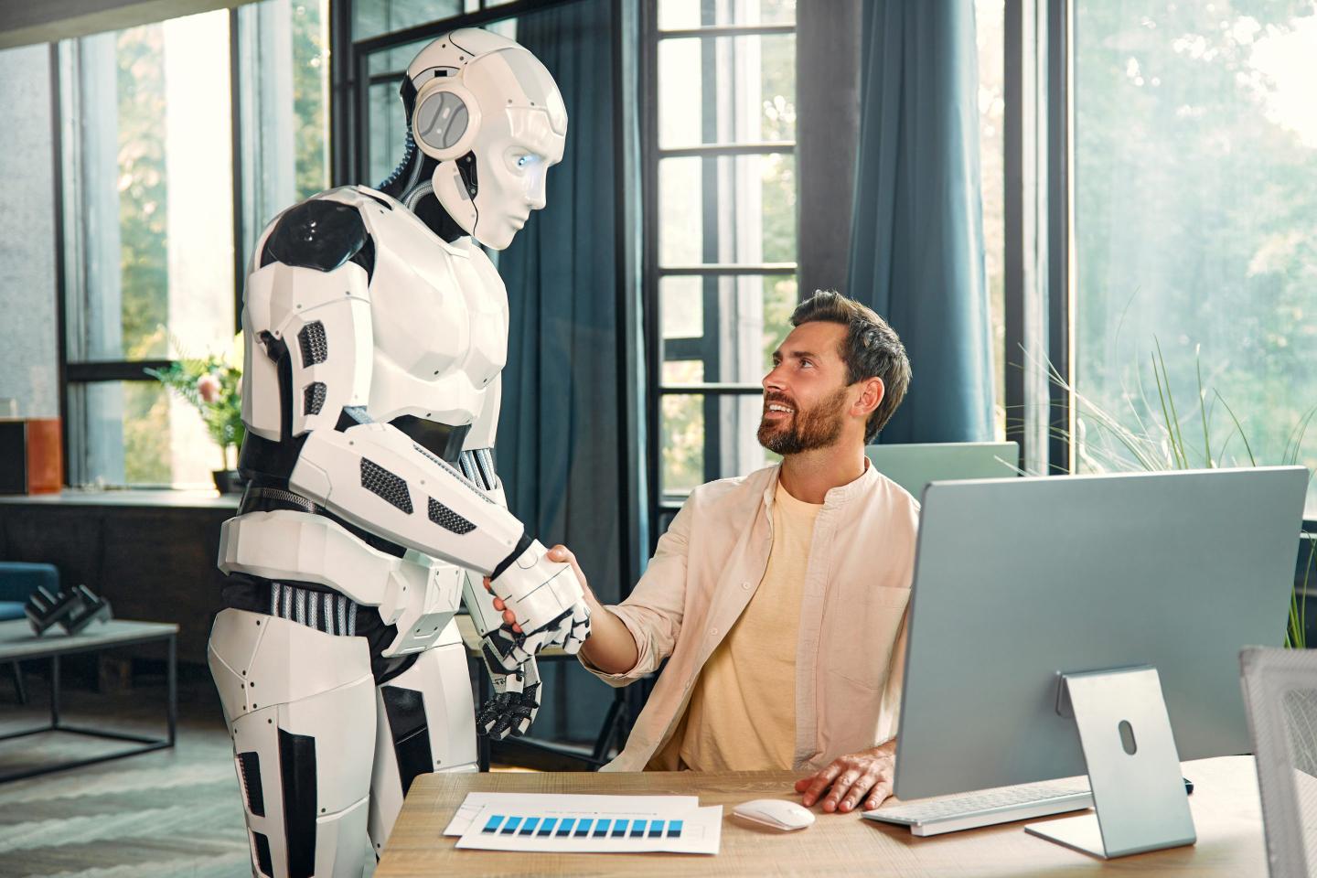Robot assistant and young businessman working at a computer