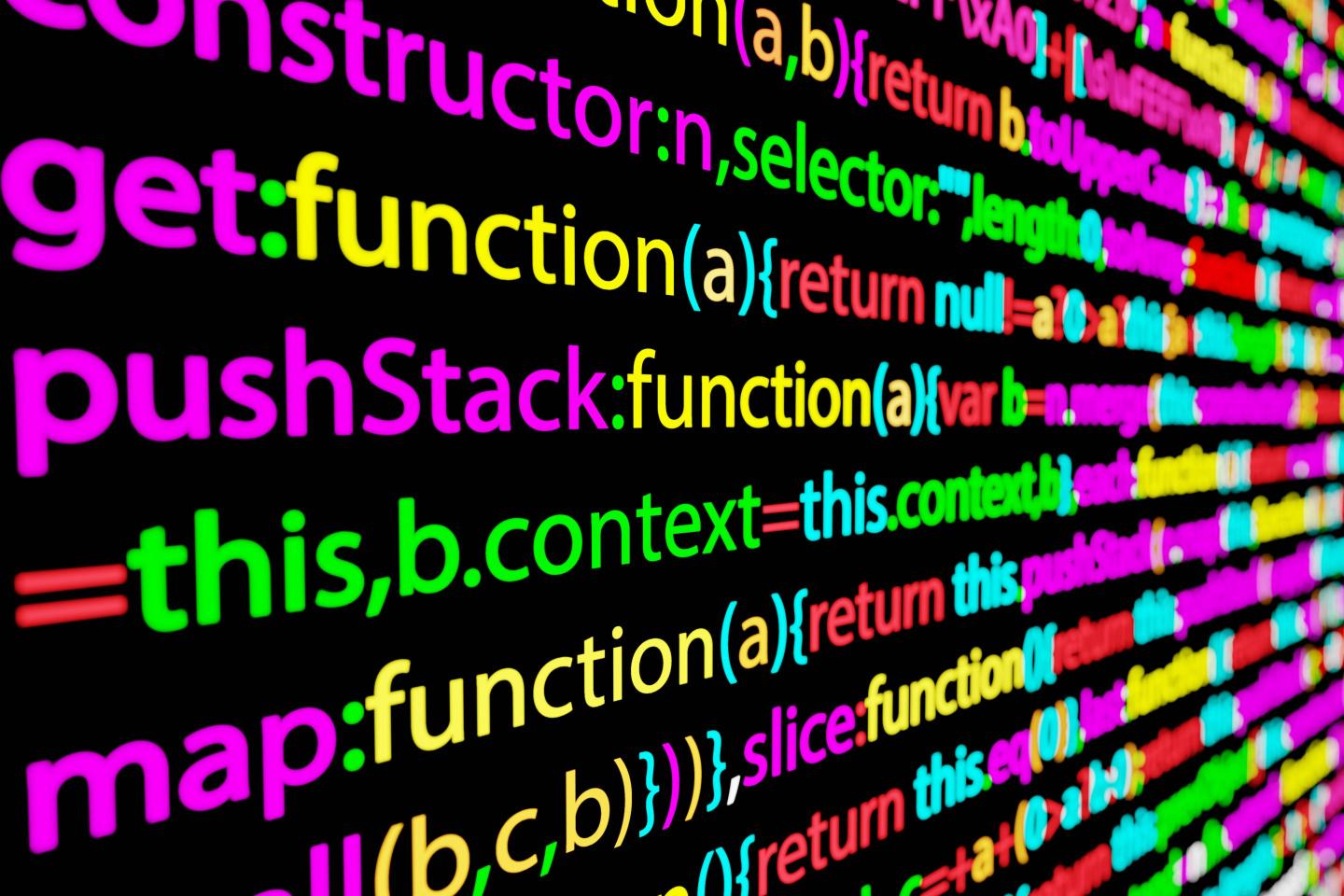 A black screen displayed at an angle on which is displayed lines of code in multiple colors.