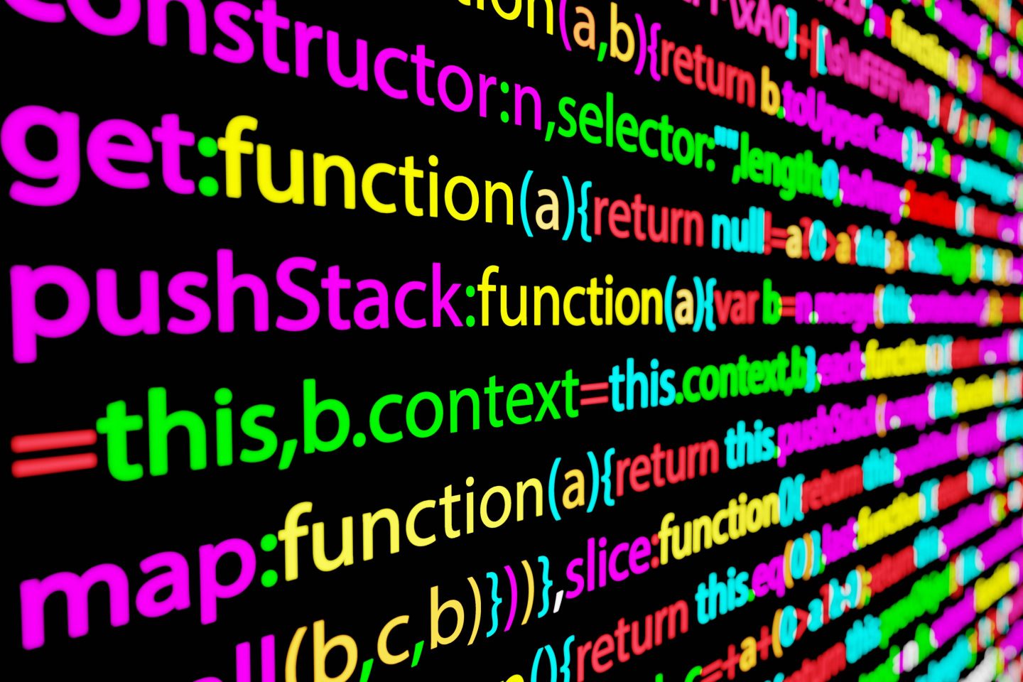 A black screen displayed at an angle on which is displayed lines of code in multiple colors.