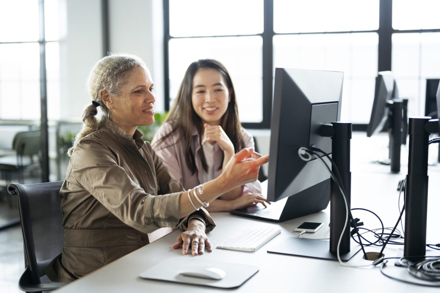 Businesswomen working together on laptop and desktop pc