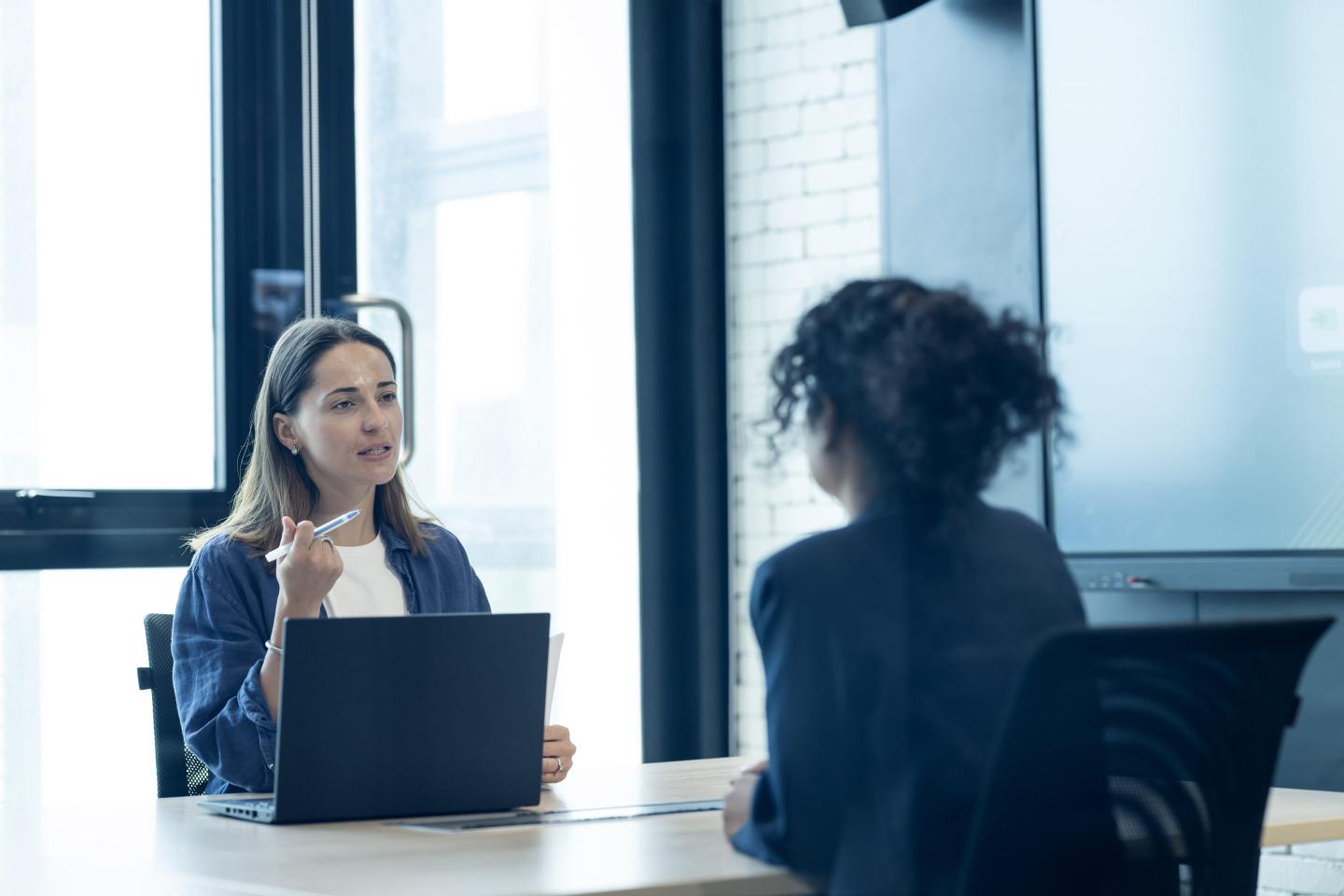 Manager conducting an interview and considering women for a new hire in a meeting room of a modern business office.