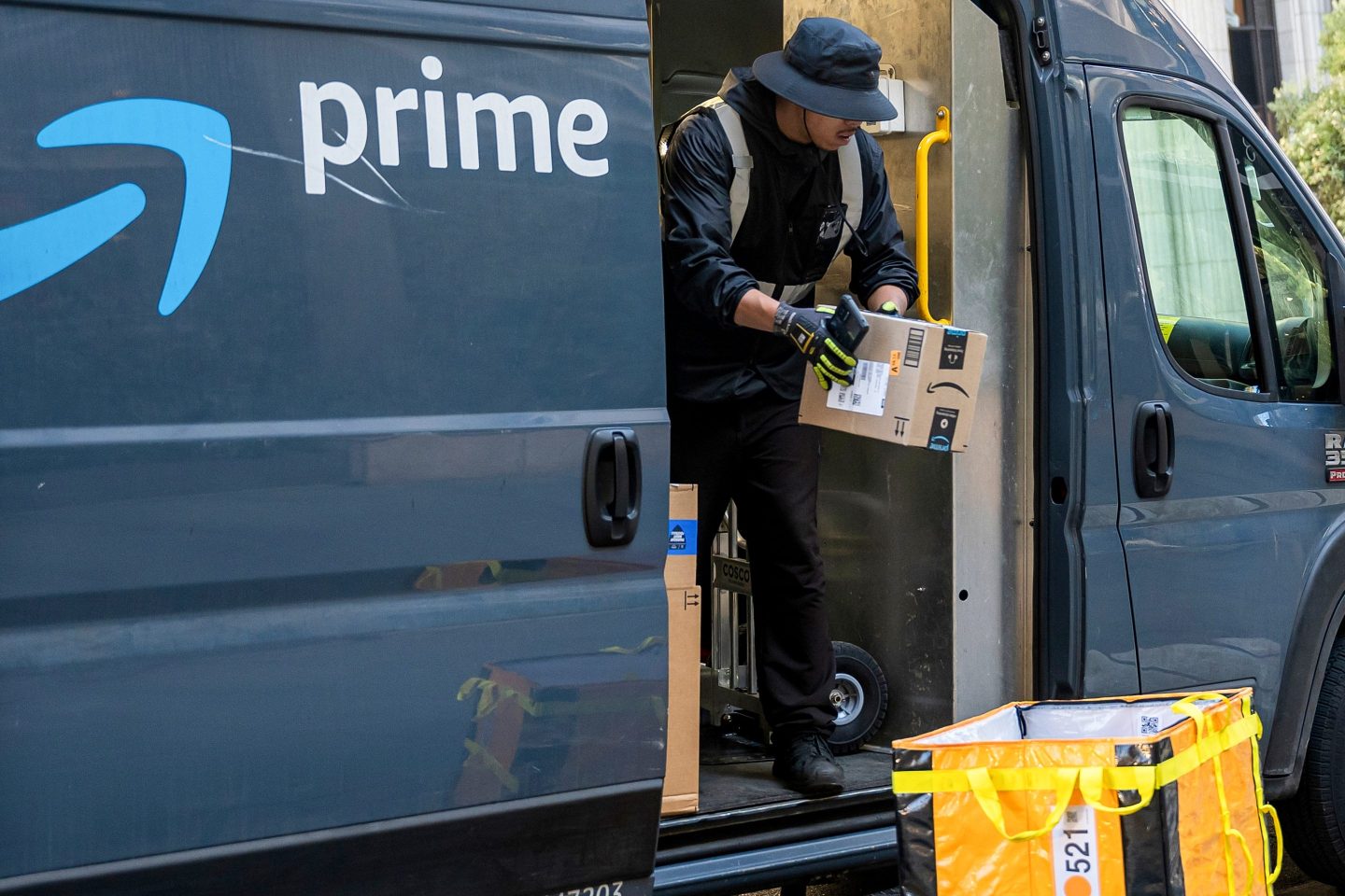 A worker unloads boxes from an Amazon delivery van