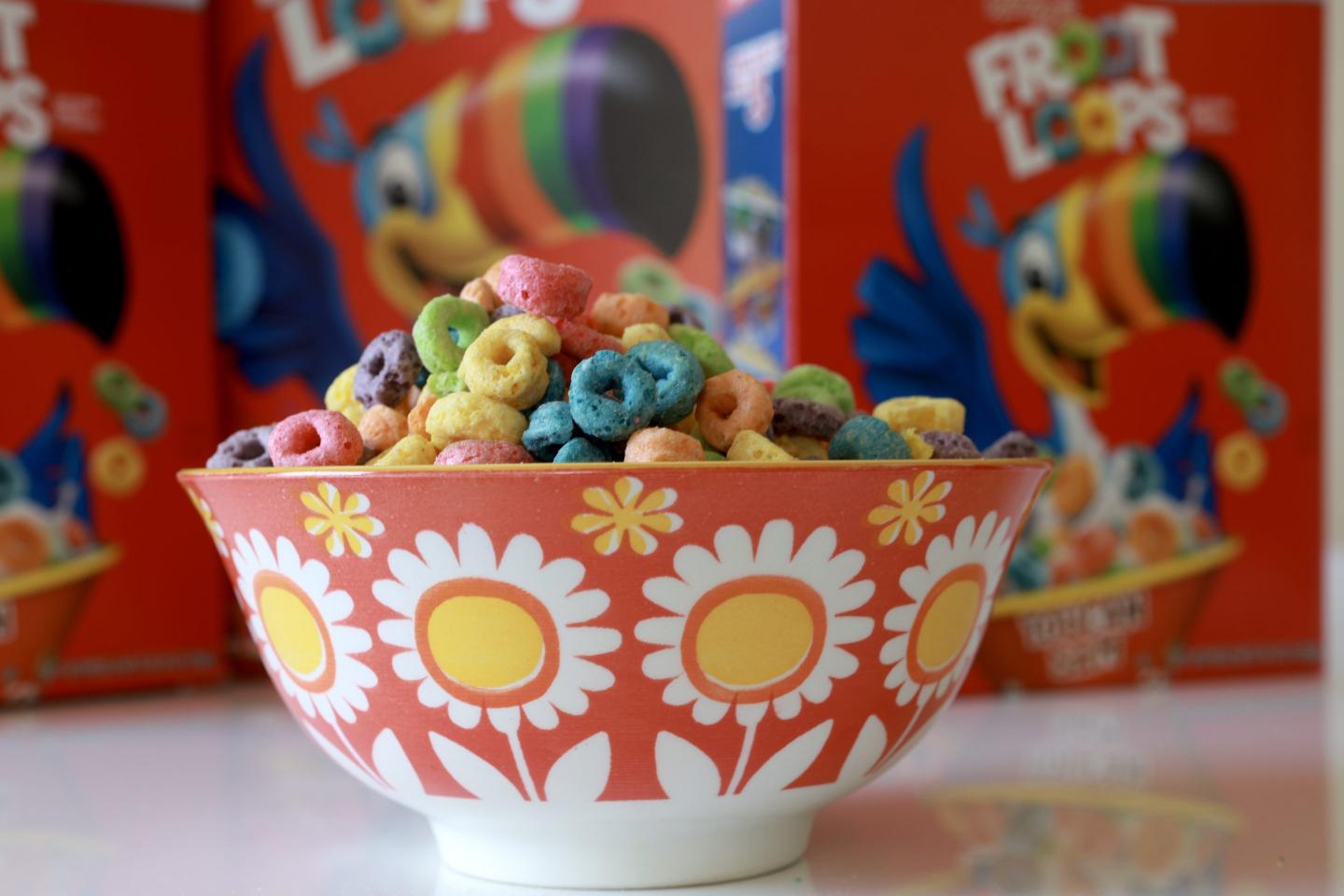 A bowl of Froot Loops in front of two Froot Loops cereal boxes