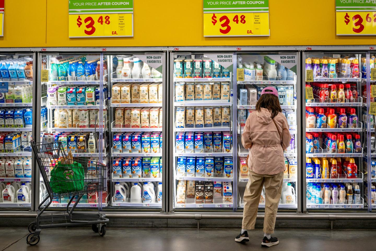 Woman stands in front a the dairy section in a grocery store.
