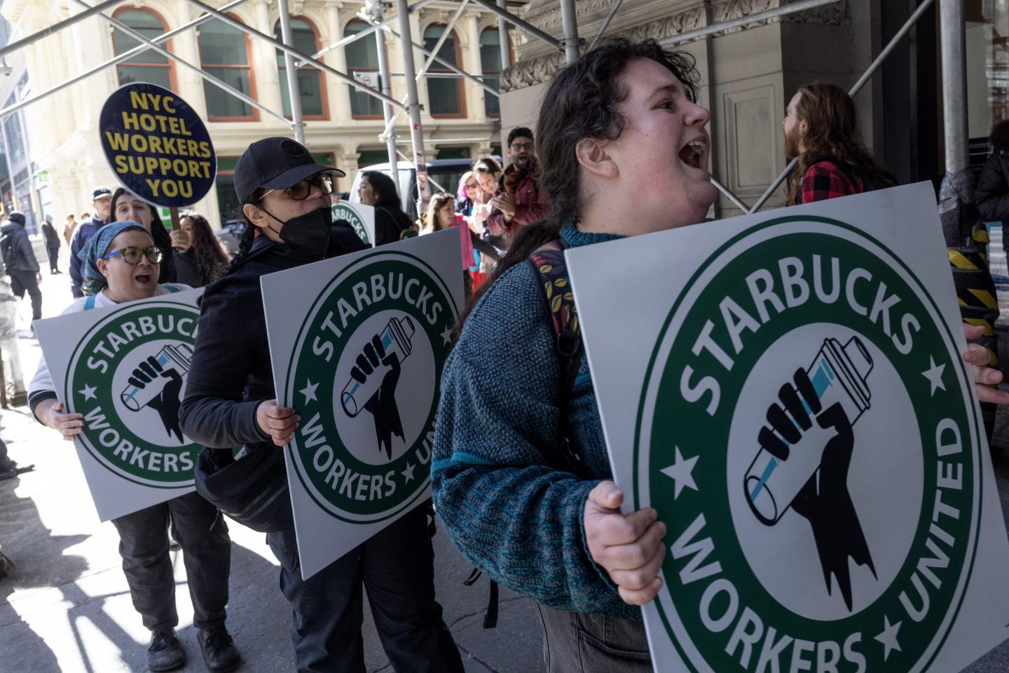 Workers march and hold signs reading, "Starbucks Workers United."
