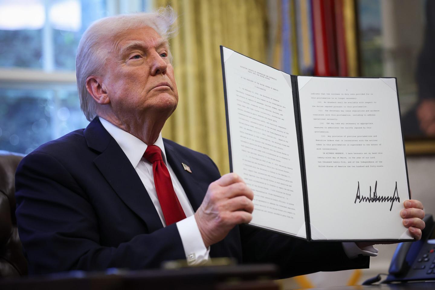 U.S. President Donald Trump displays a signed an executive order in the Oval Office of the White House on March 26, 2025 in Washington, DC. President Trump announced 25% tariffs on all foreign-made cars.