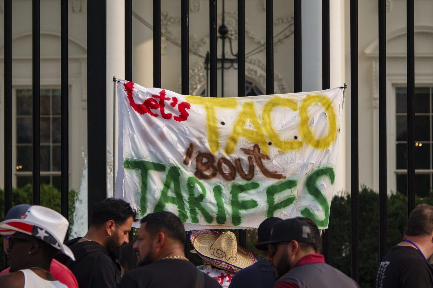 A protestor holds a sign that says "Let's Taco 'bout Tariffs" outside of the White House on June 3.