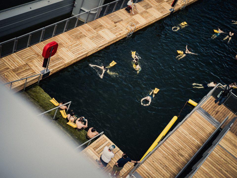 Overhead view from the Passerelle Simone de Beauvoir of the first people swimming in the Seine at the safe bathing site at Bercy.