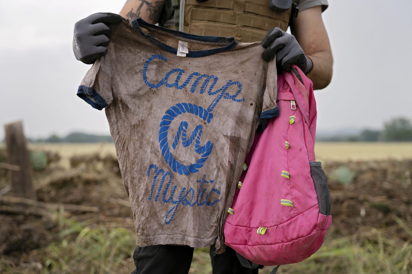 A rescue volunteer holds up a shirt that says "Camp Mystic"