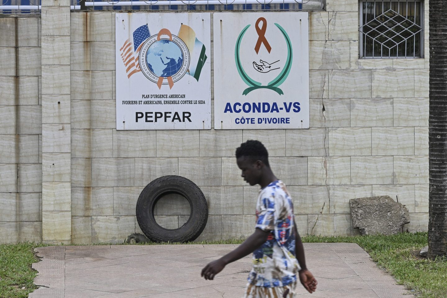 A pedestrian walks past a PEPFAR sign