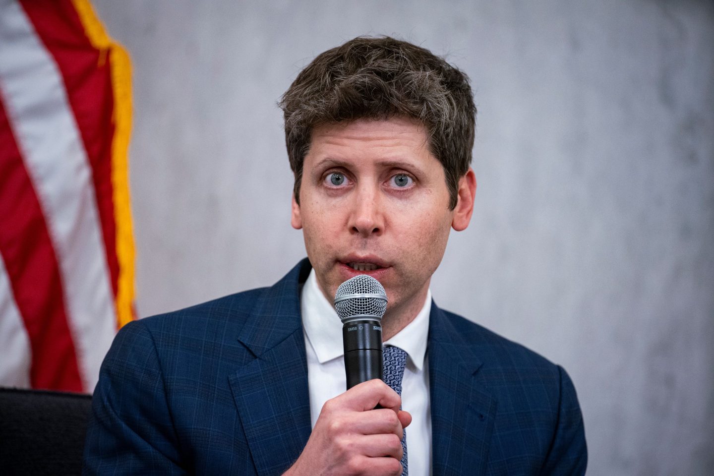 Sam Altman holds a microphone