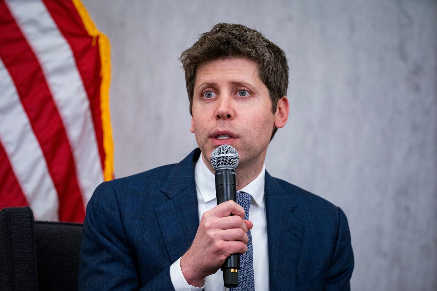 Sam Altman holds a microphone