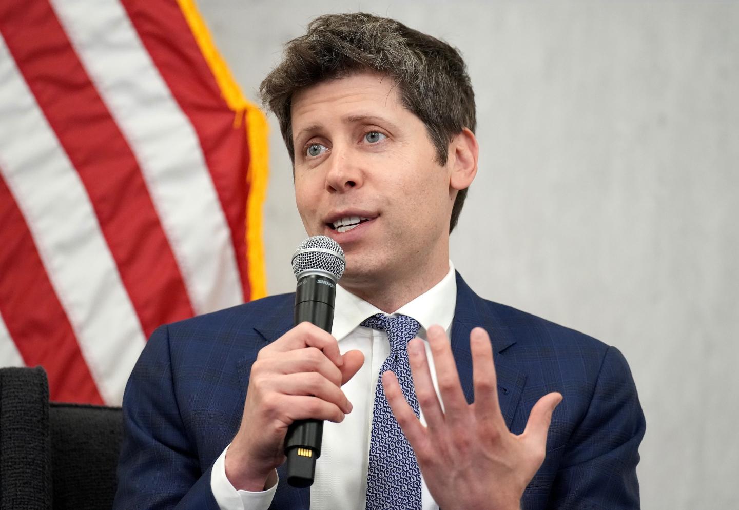Sam Altman holds a microphone in hand