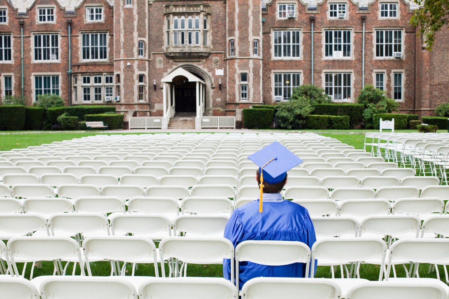 Graduate sitting alone in outside a college.