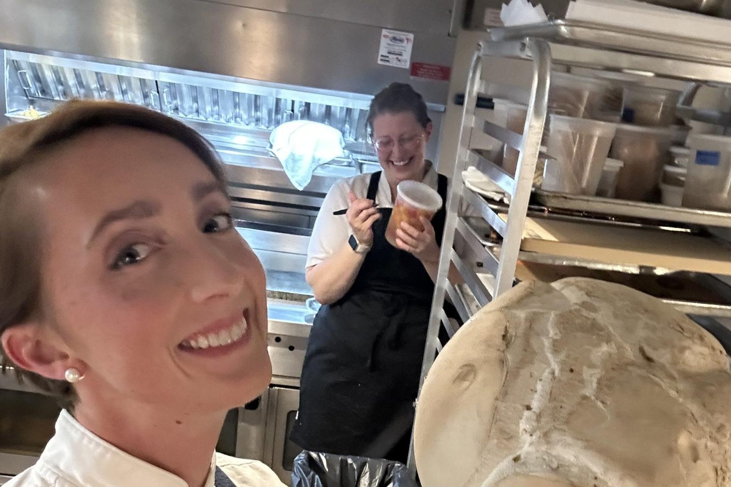 Karyn Tomlinson poses in a kitchen with another chef smiling behind her