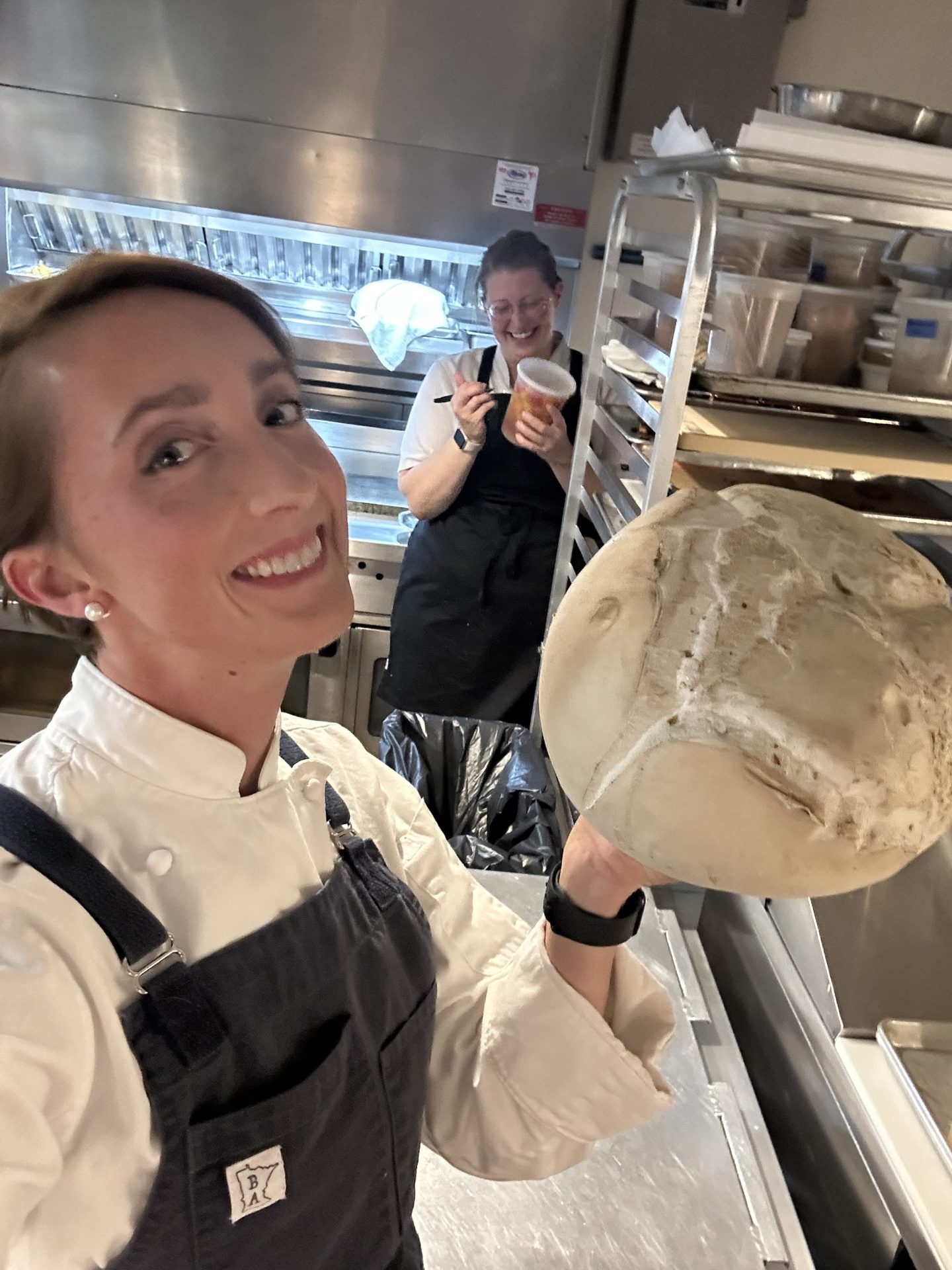 Karyn Tomlinson poses in a kitchen with another chef smiling behind her