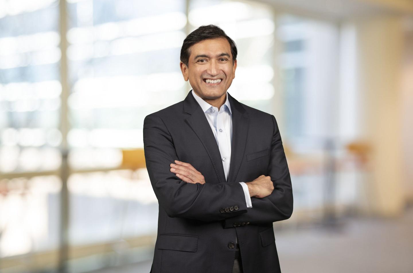 Shailesh Jejurikar standing in a suit in front of a window.