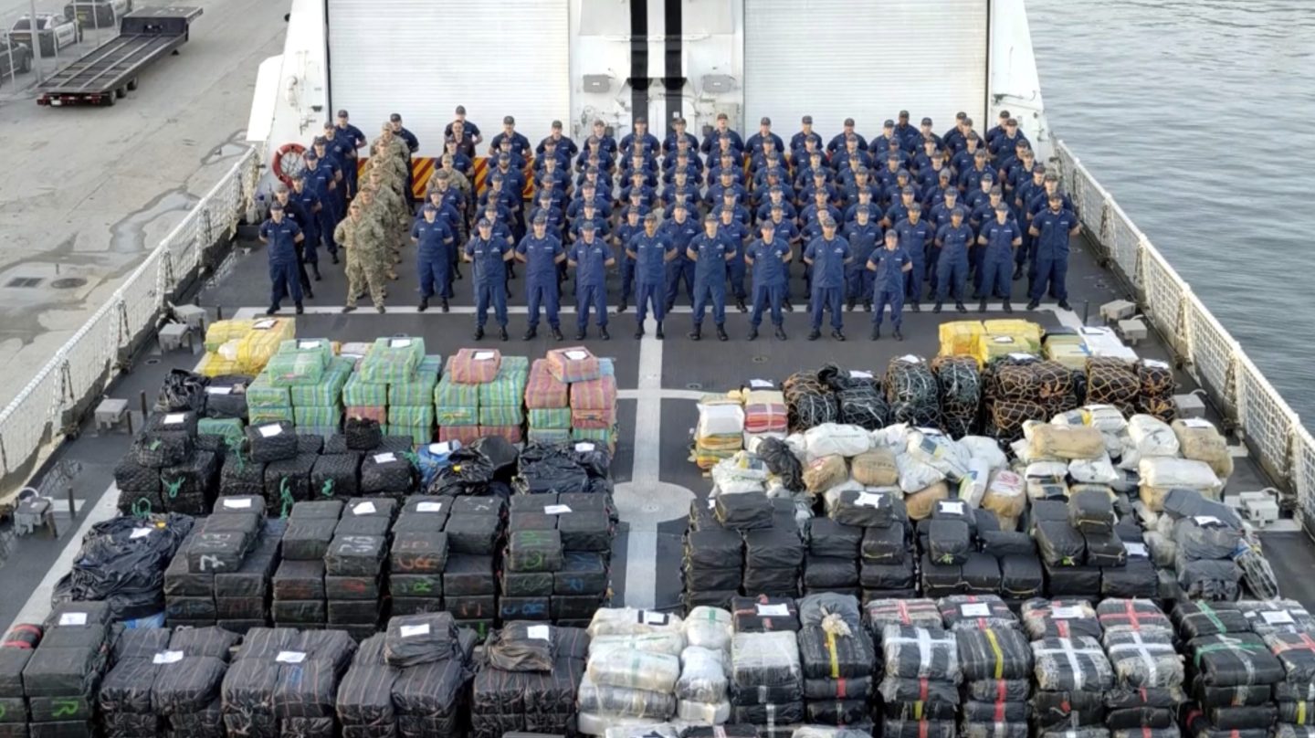 U.S. Coast Guards stand at attention behind their haul of drugs that they seized.