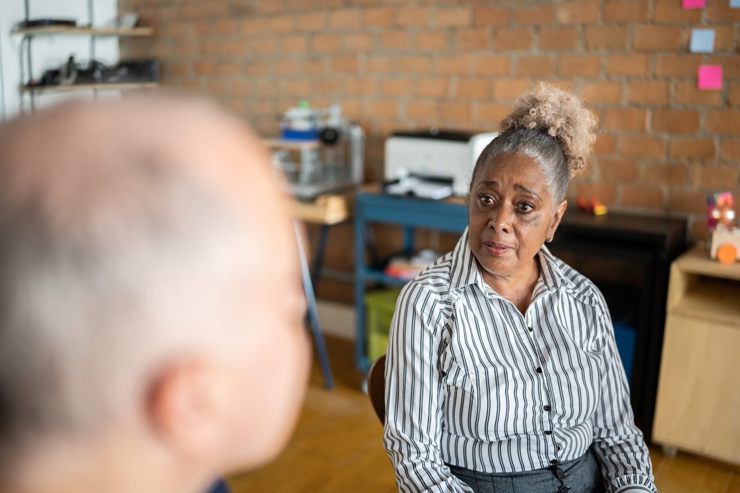 A woman in a stripe shirt looks concerned at a man on the left hand side