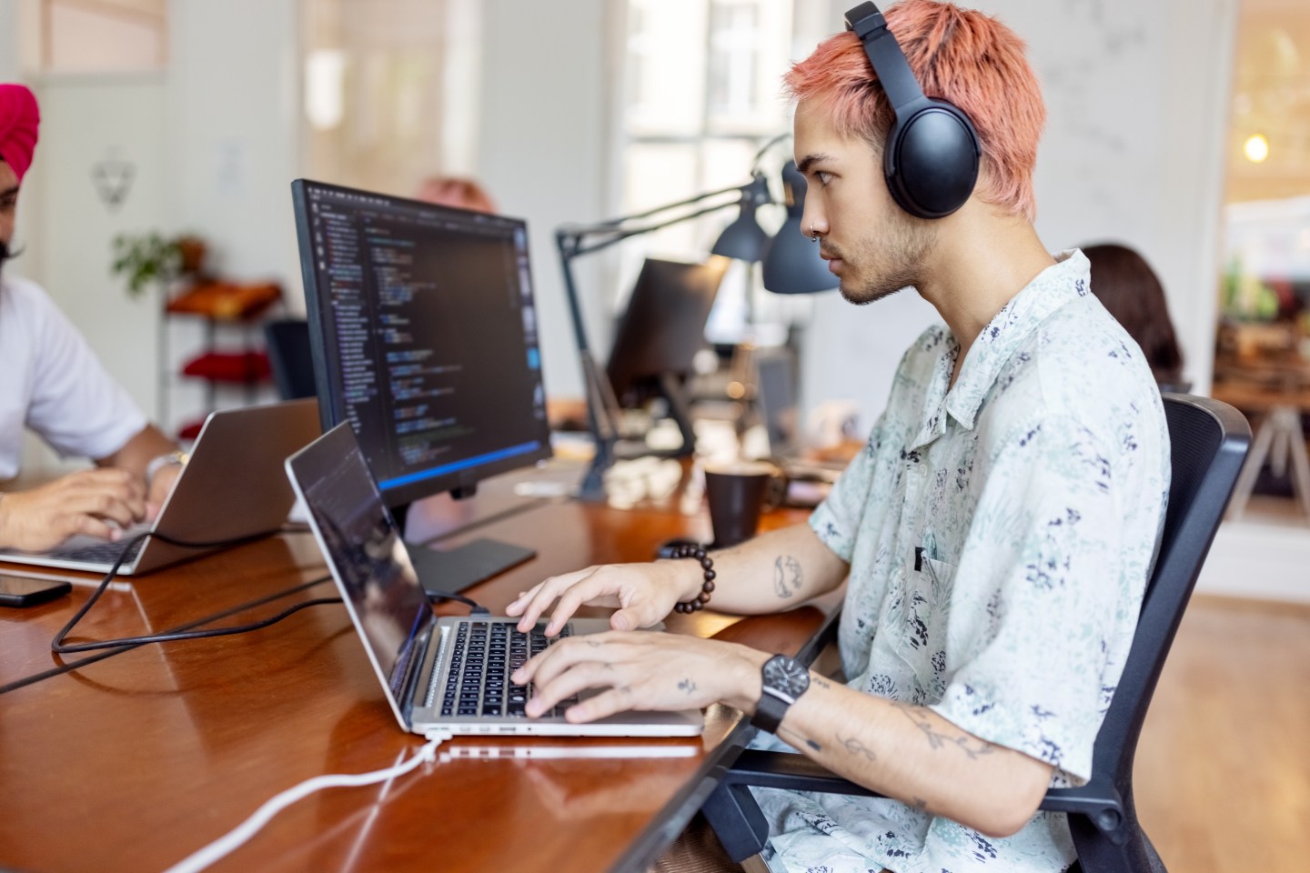 Young man wearing headphones working on computer at startup office