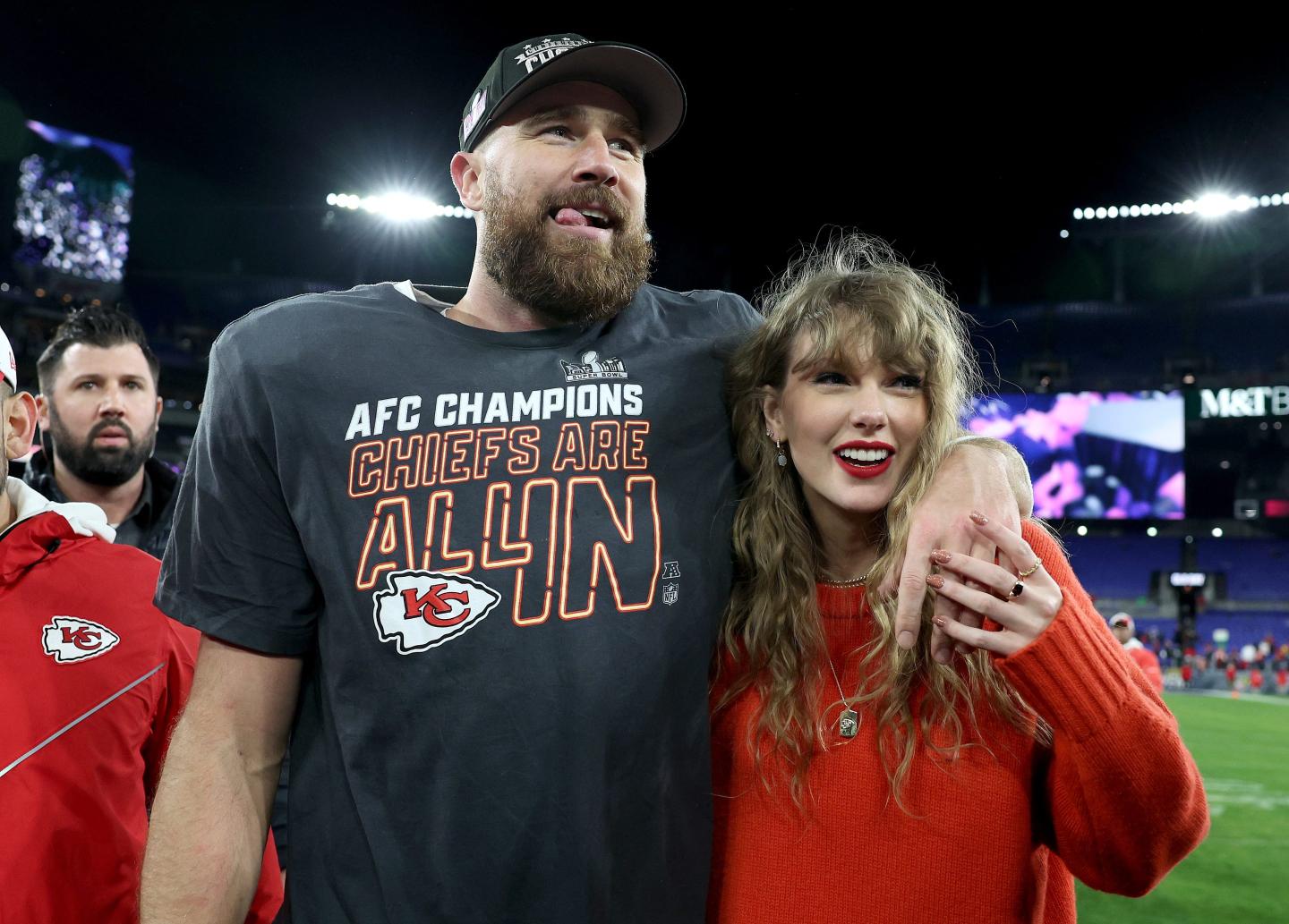 Travis Kelce wraps his arm around Taylor Swift on the football field