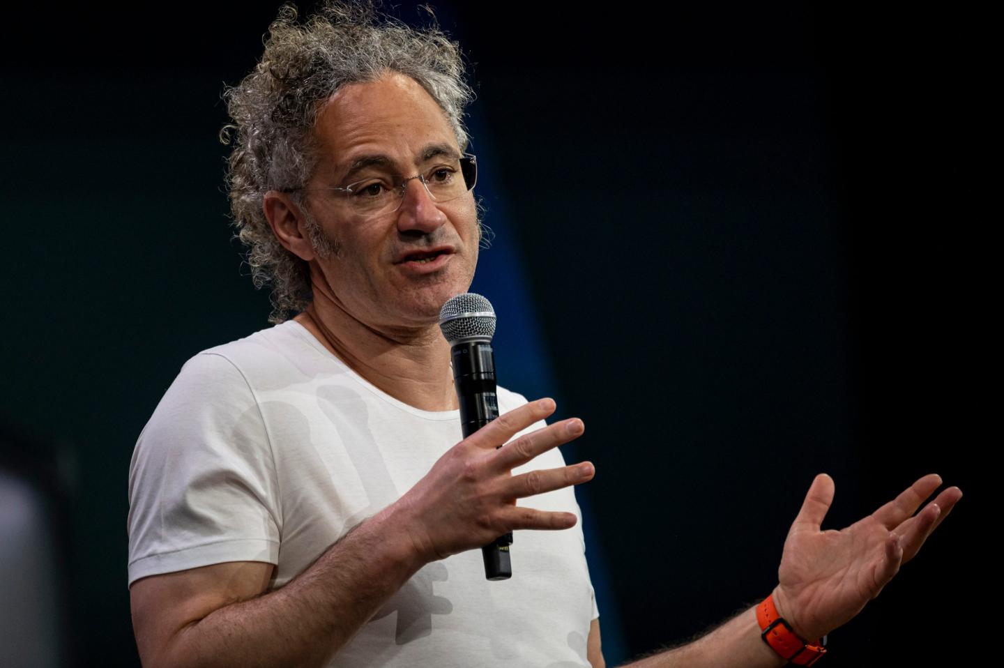 Alex Karp gestures while holding a microphone