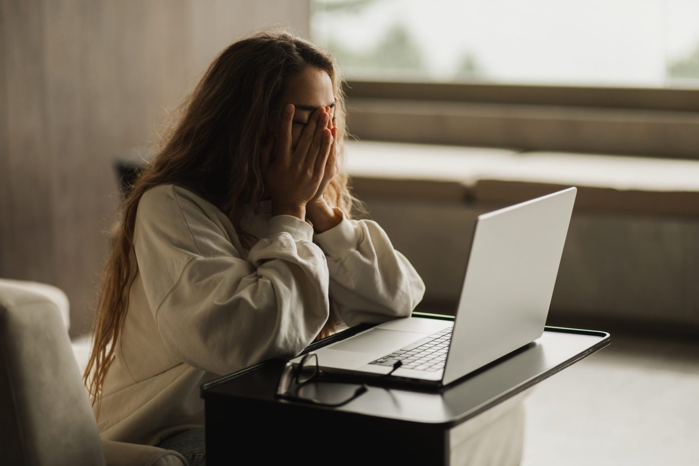 Woman working on a laptop with her head in her hands
