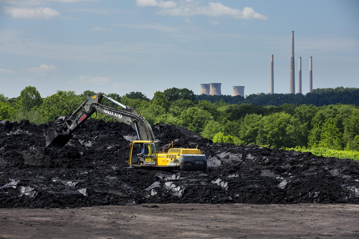 With the shuttered Homer City coal plant in the background, at the Lucerne Reclamation project site in Pennsylvania, a worker moves coal refuse to be prepared for transport to be cleaned on June 12, 2024. The soil, contaminated by coal refuse, is cleaned and returned to the land where it is encased and covered with top soil and planted as a meadow.