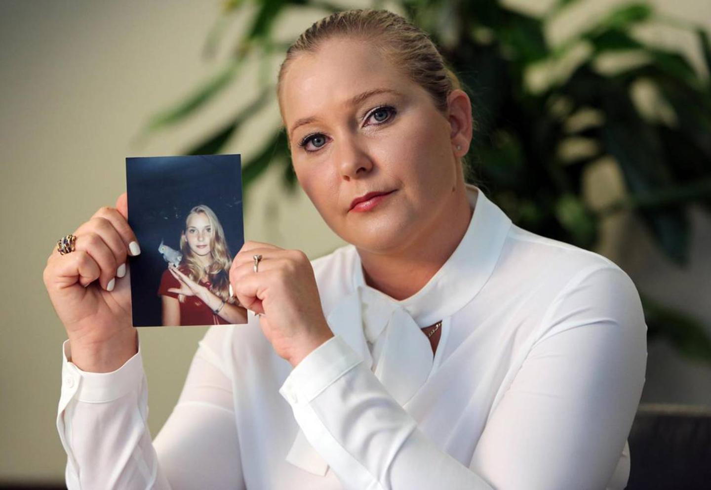 Virginia Giuffre holds a photo of herself as a teen