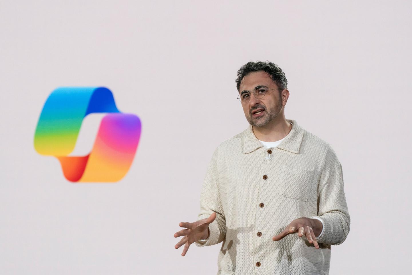 Mustafa Suleyman standing on stage in front of the Microsoft logo.