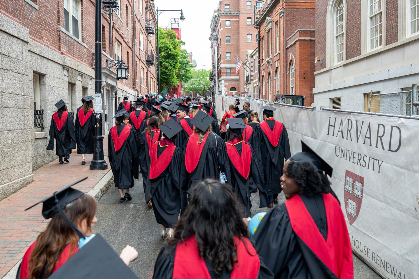 Harvard grads walk down a narrow street.
