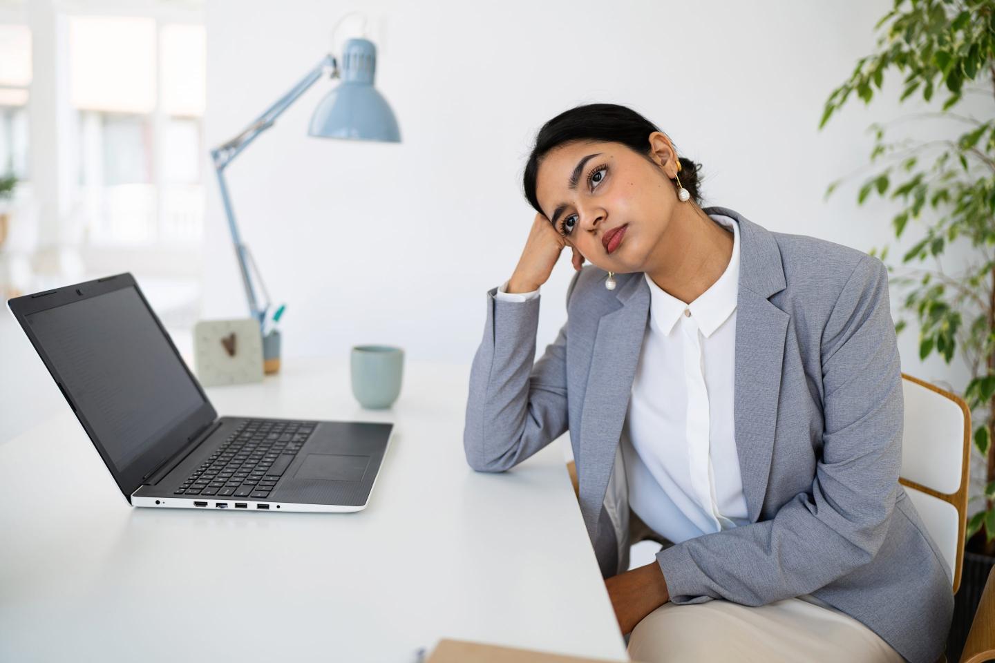Young woman at desk, daydreaming