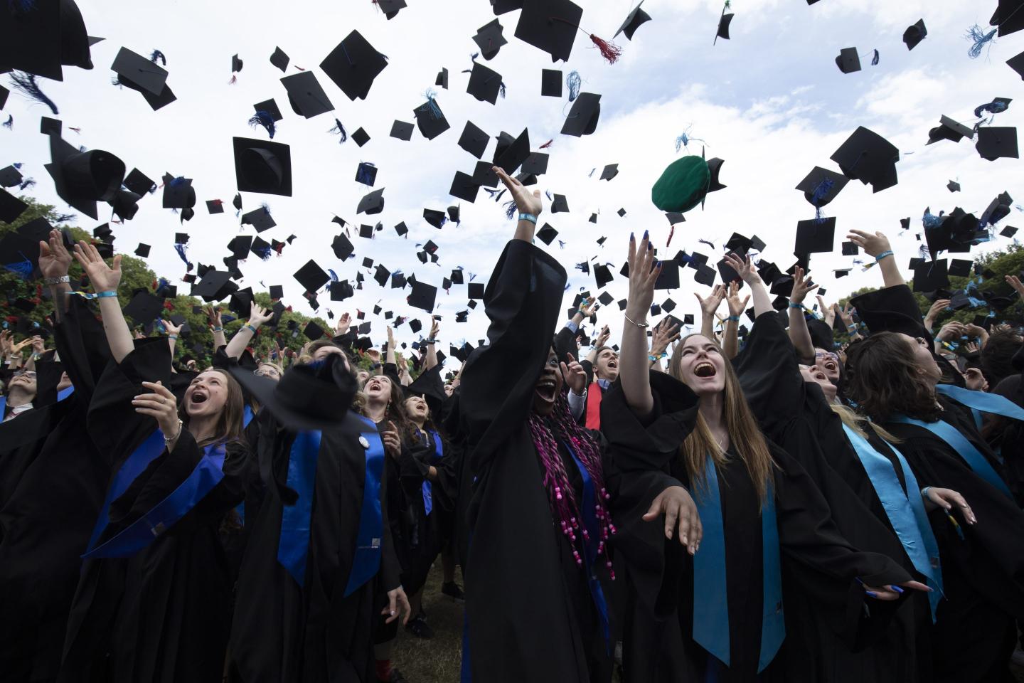 Graduates throw their caps in the air.